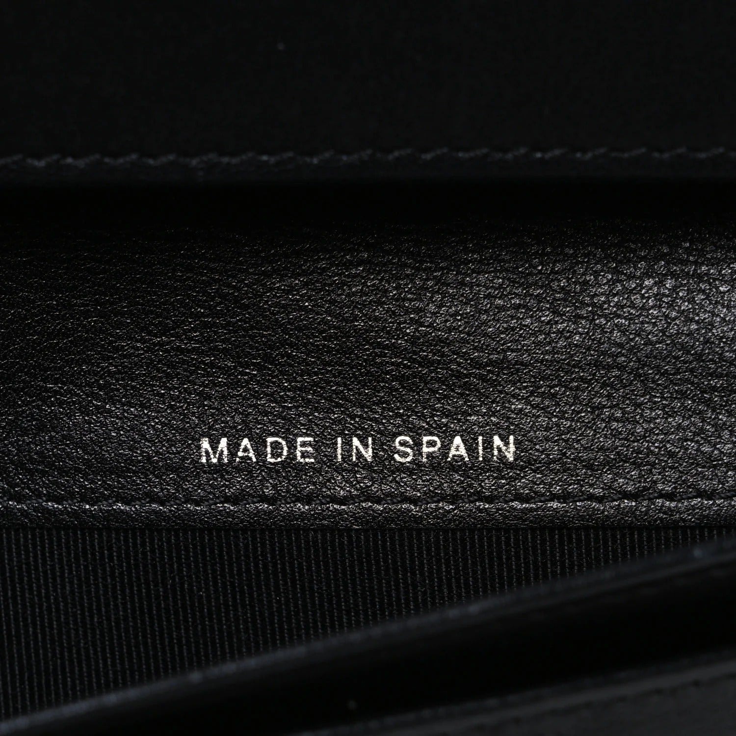 Black leather surface with 'MADE IN SPAIN' text