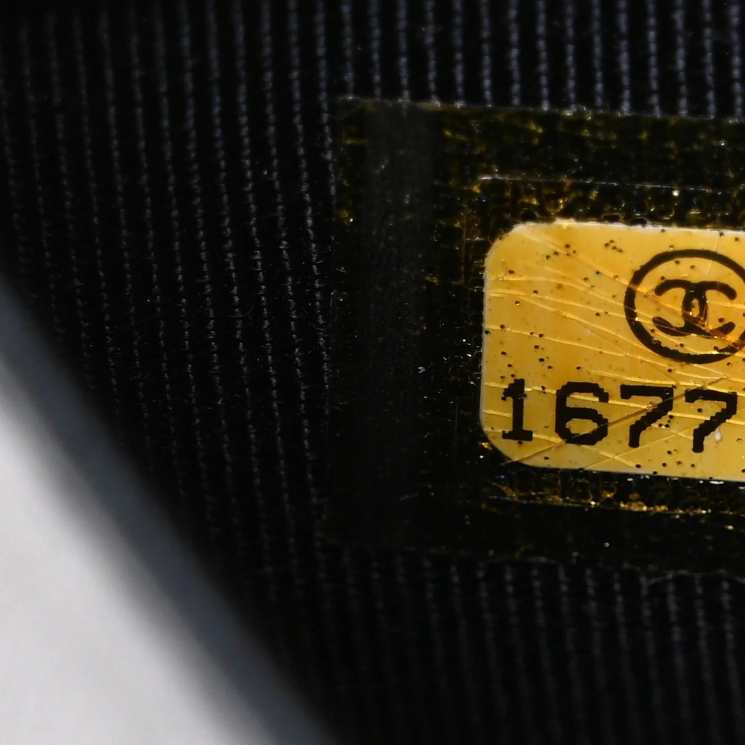 Close-up of a black fabric surface with a yellow label featuring a logo and number '1677'.