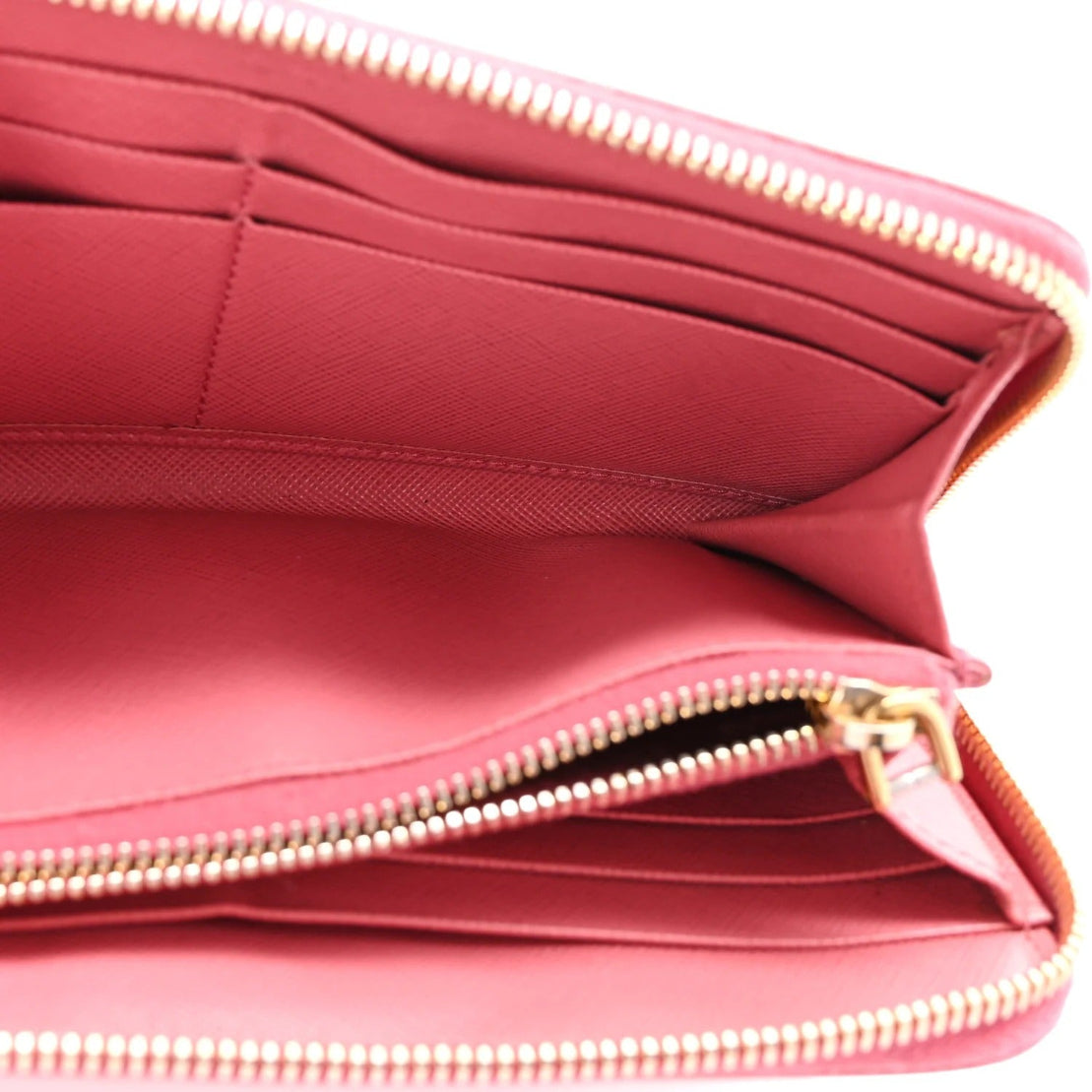 Close-up of a pink handbag with gold zipper details on a white background