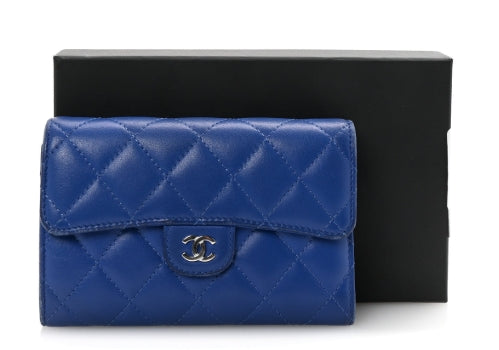 Blue quilted wallet with Chanel logo in front of a black box on a white background