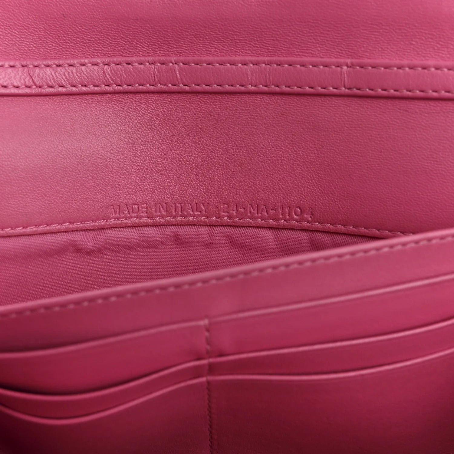 Close-up of a pink leather product with 'Made in Italy' label.