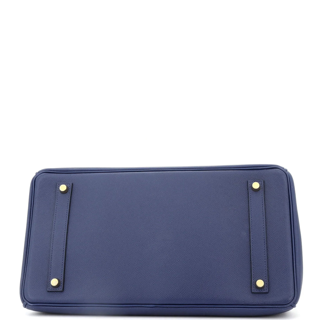 Underside of Blue Hermes Birkin bag with gold accents on a white background