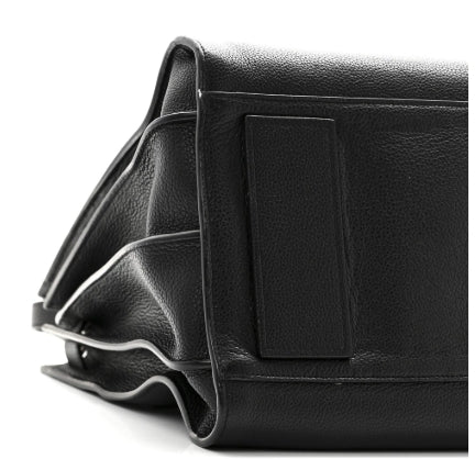Close-up of a black leather bag with a strap on a white background