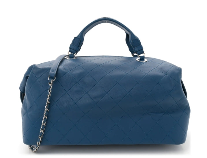 Blue quilted handbag with a chain detail on a white background