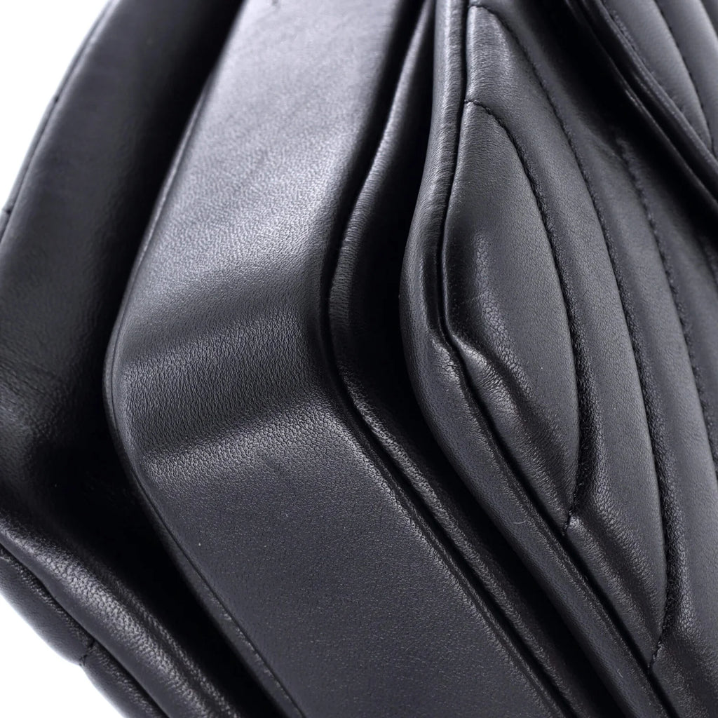 Close-up of a black classic Chanel leather  leather bag with folds on a white background