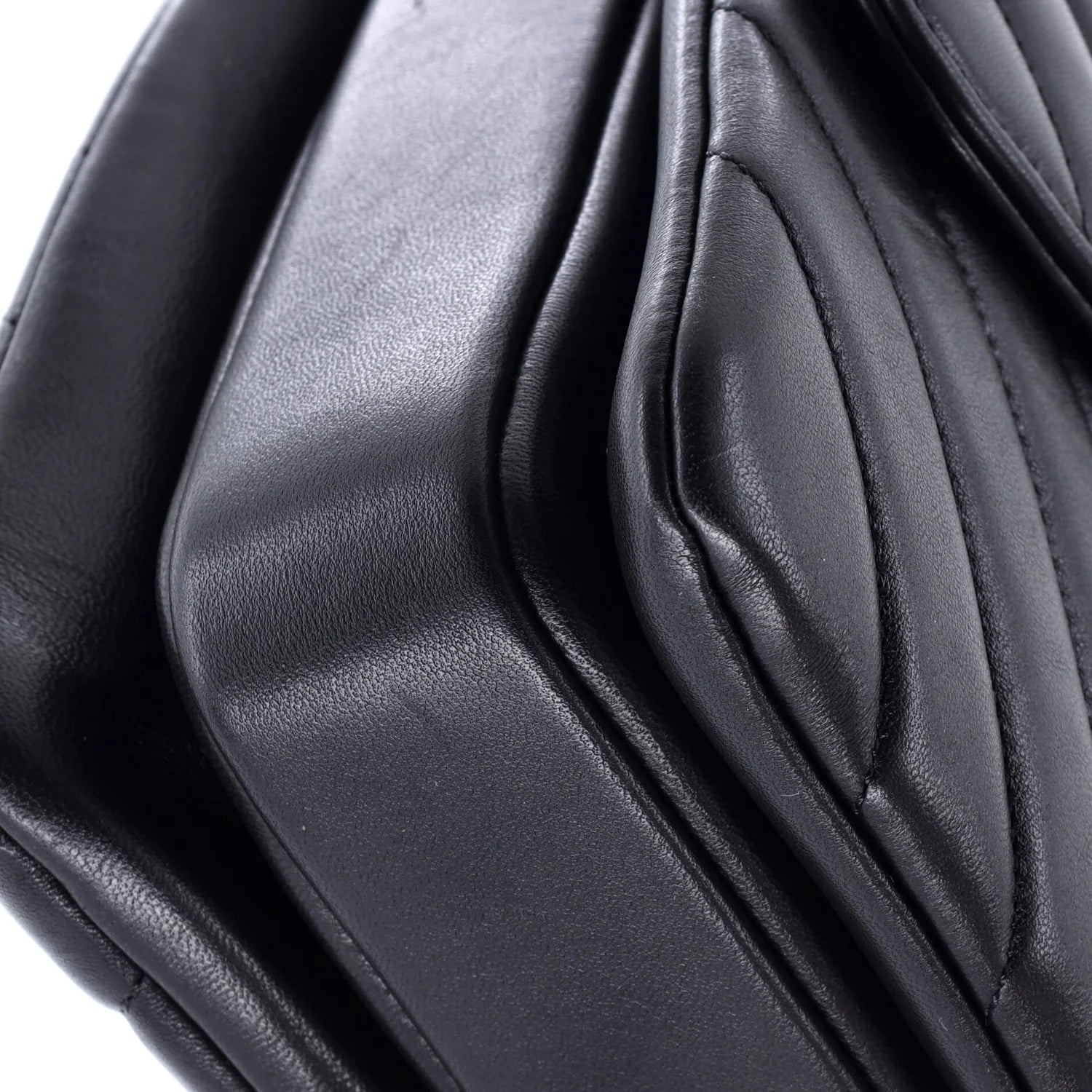 Close-up of a black classic Chanel leather  leather bag with folds on a white background