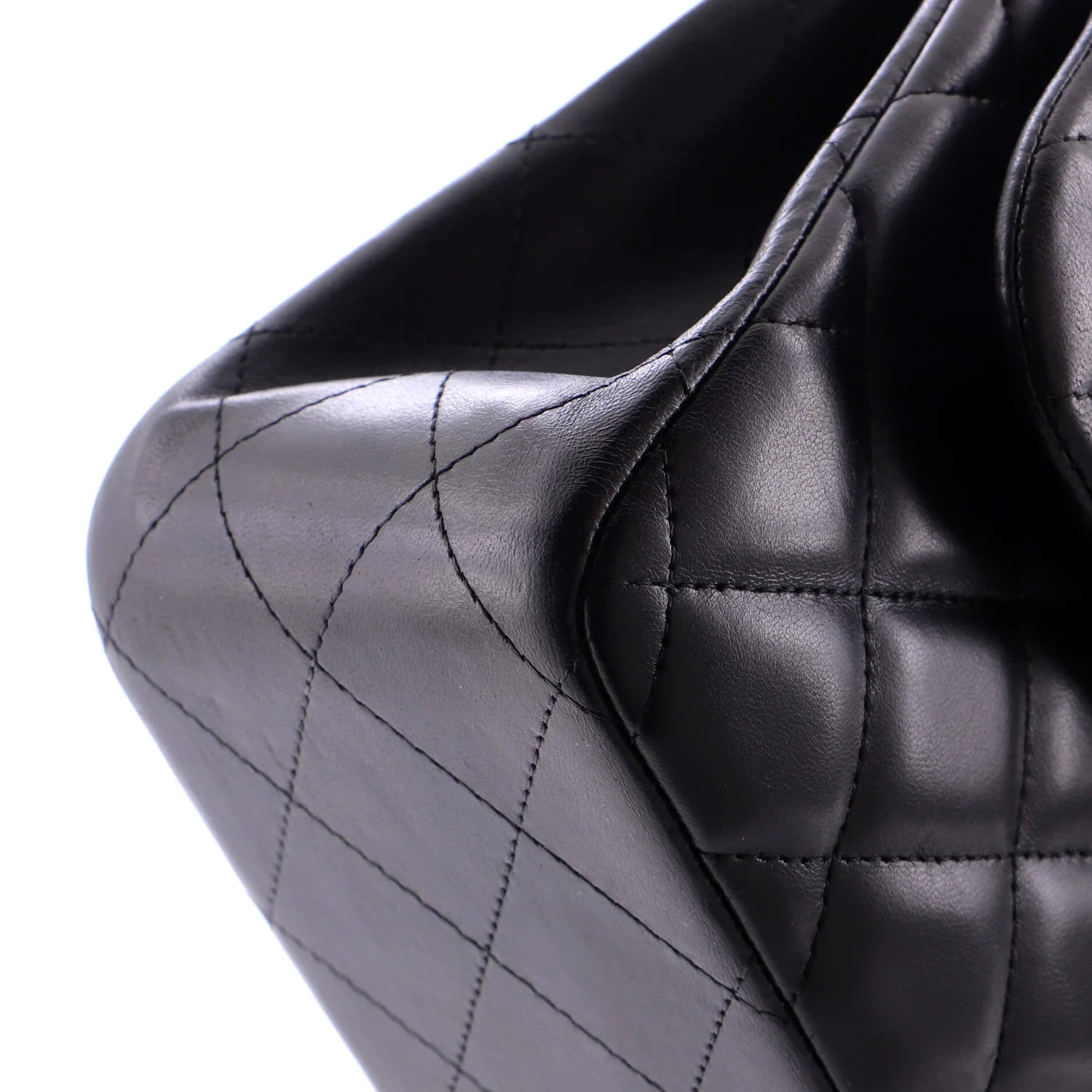 Close-up of a black quilted classic Chanel handbag underside on a white background
