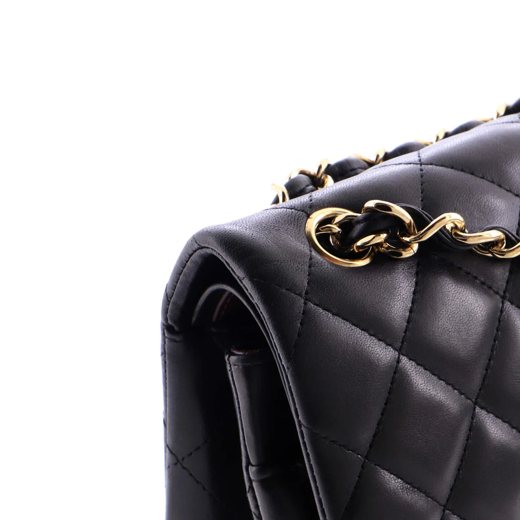 Black quilted classic Chanel handbag with gold chain detail on a white background