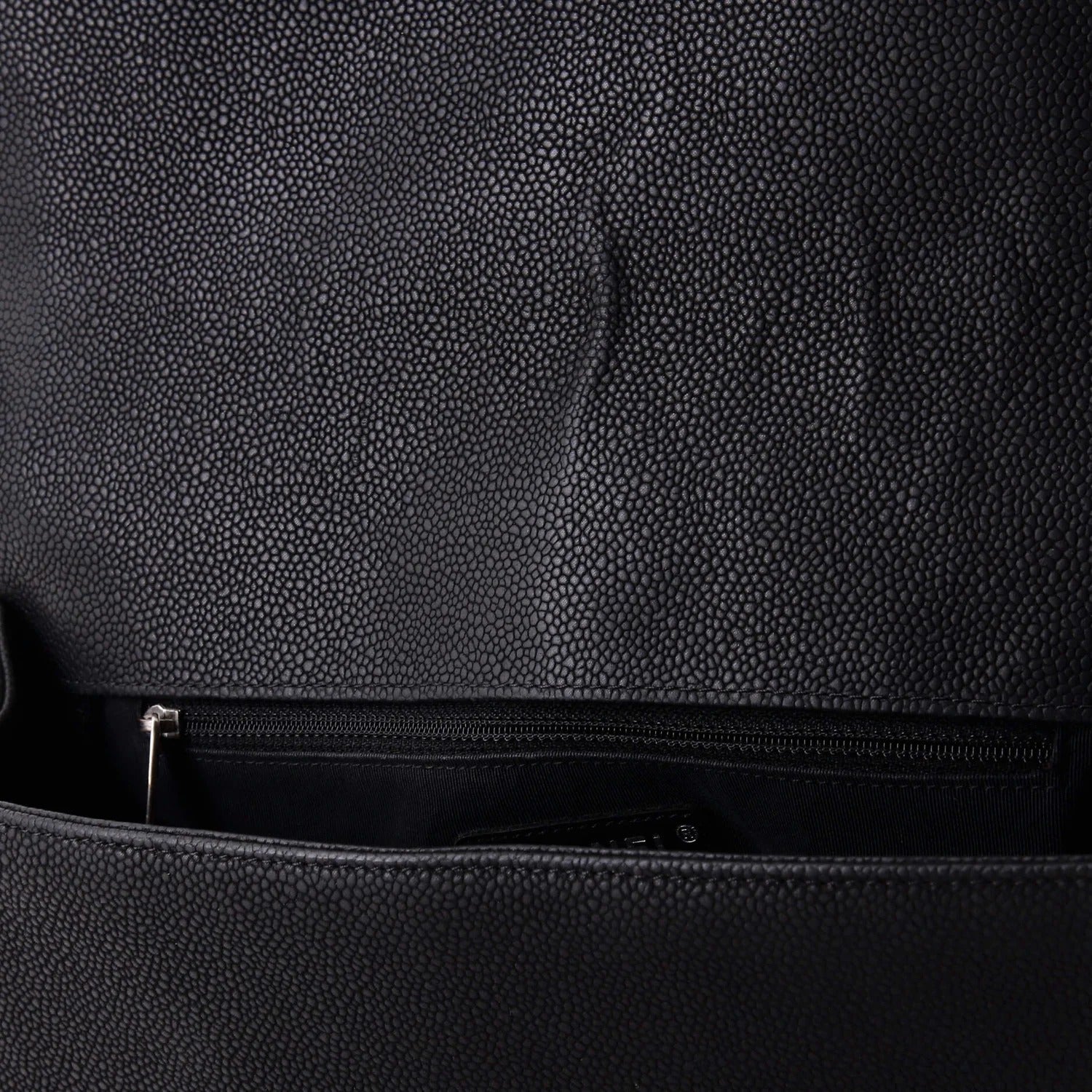 chanel caviar boy flap bag large Close-up of a textured black bag with a zipper.