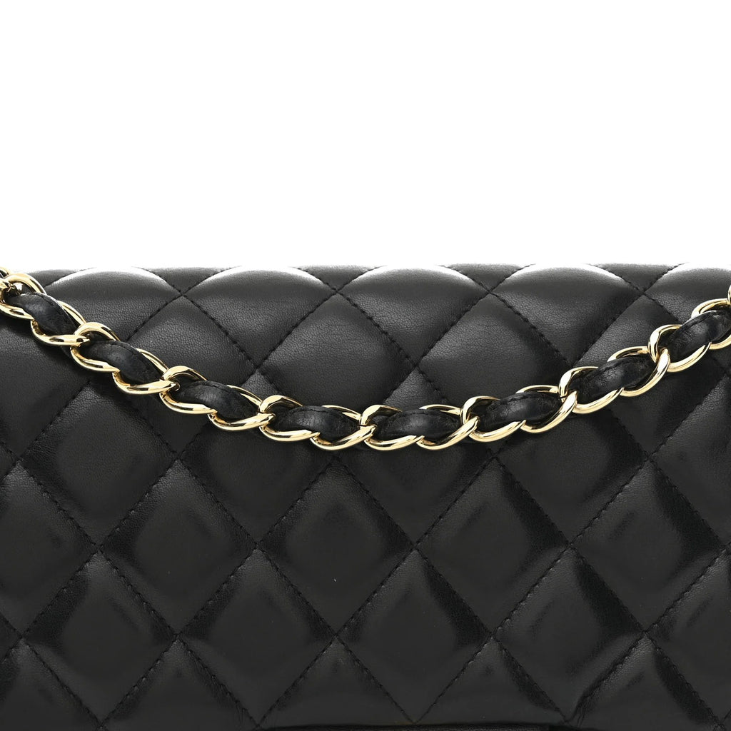 Black quilted handbag with a gold chain strap on a white background