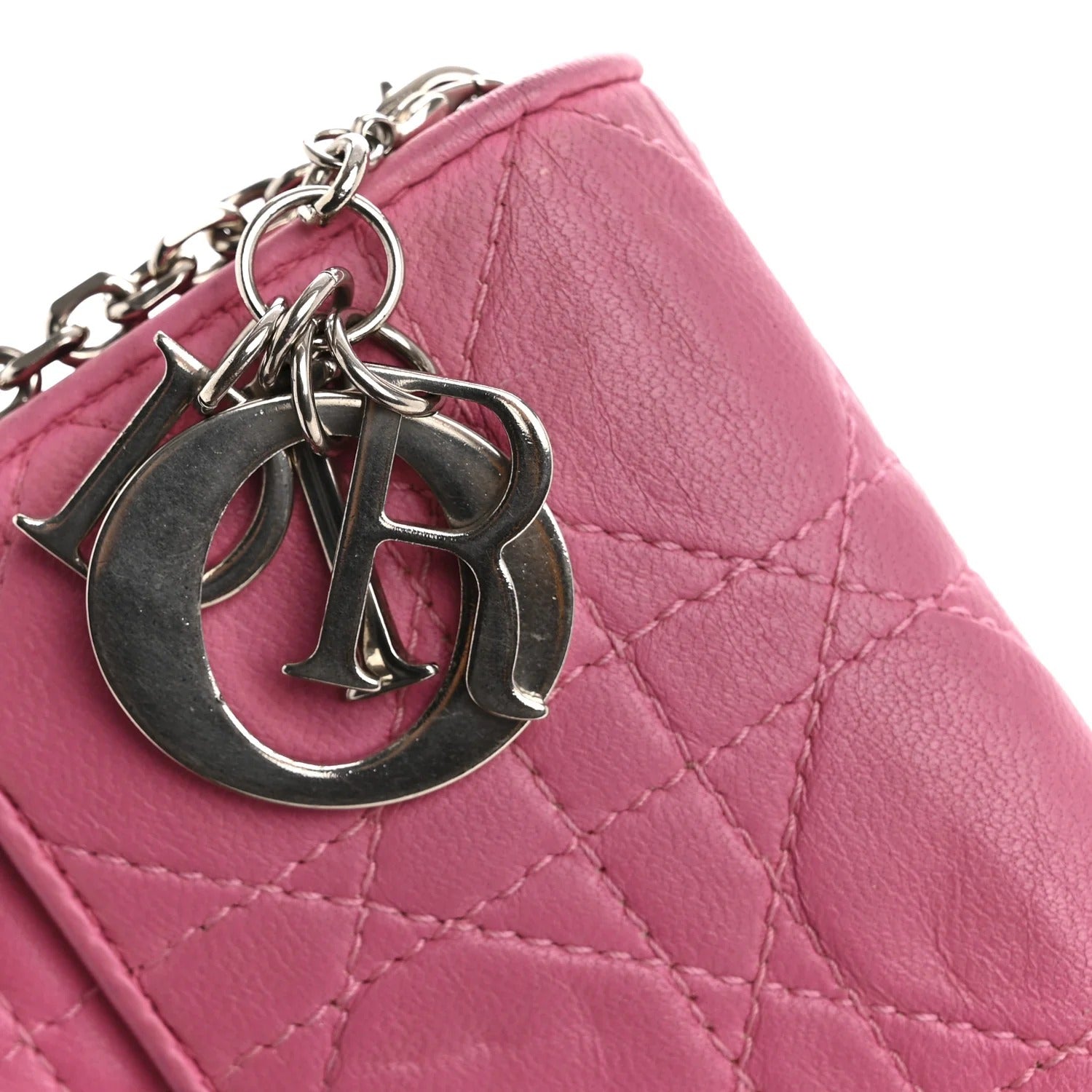 Pink quilted handbag with silver chain and charms on a white background