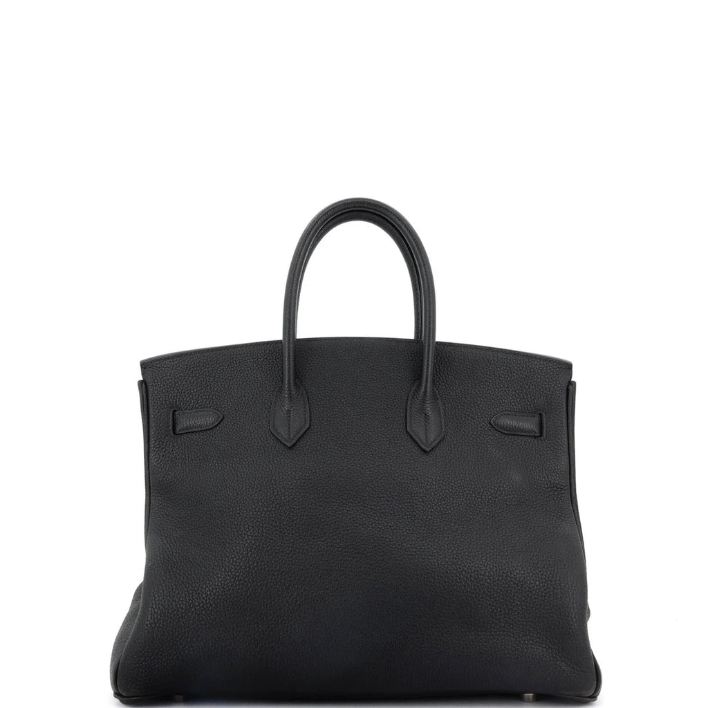 Black Hermes Birkin handbag with a glossy finish on a white background