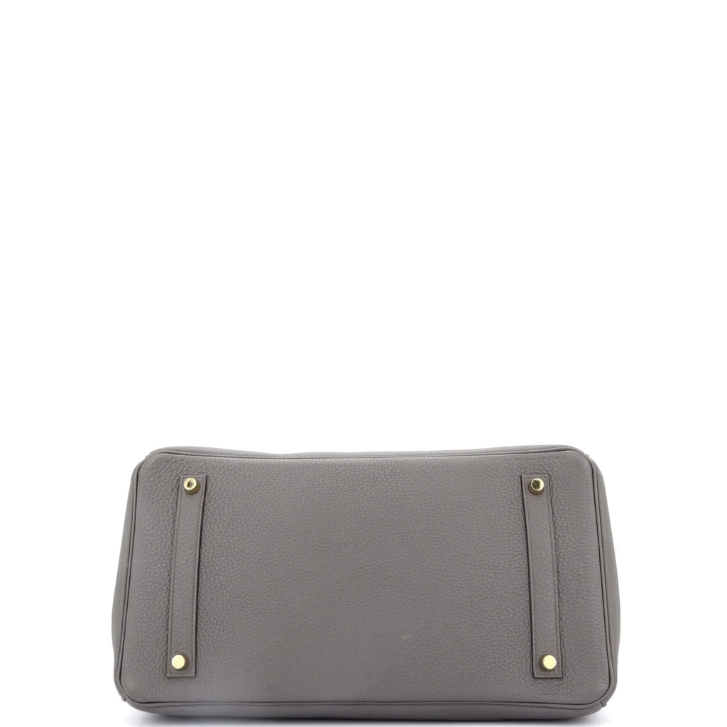 Gray Hermes Birkin handbag with gold accents on a white background