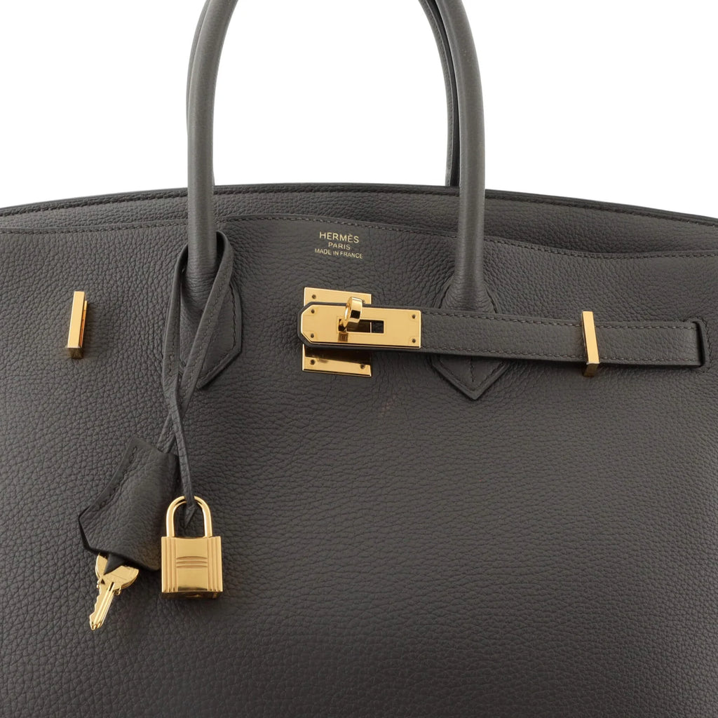 Gray Hermès handbag with gold hardware on a white background