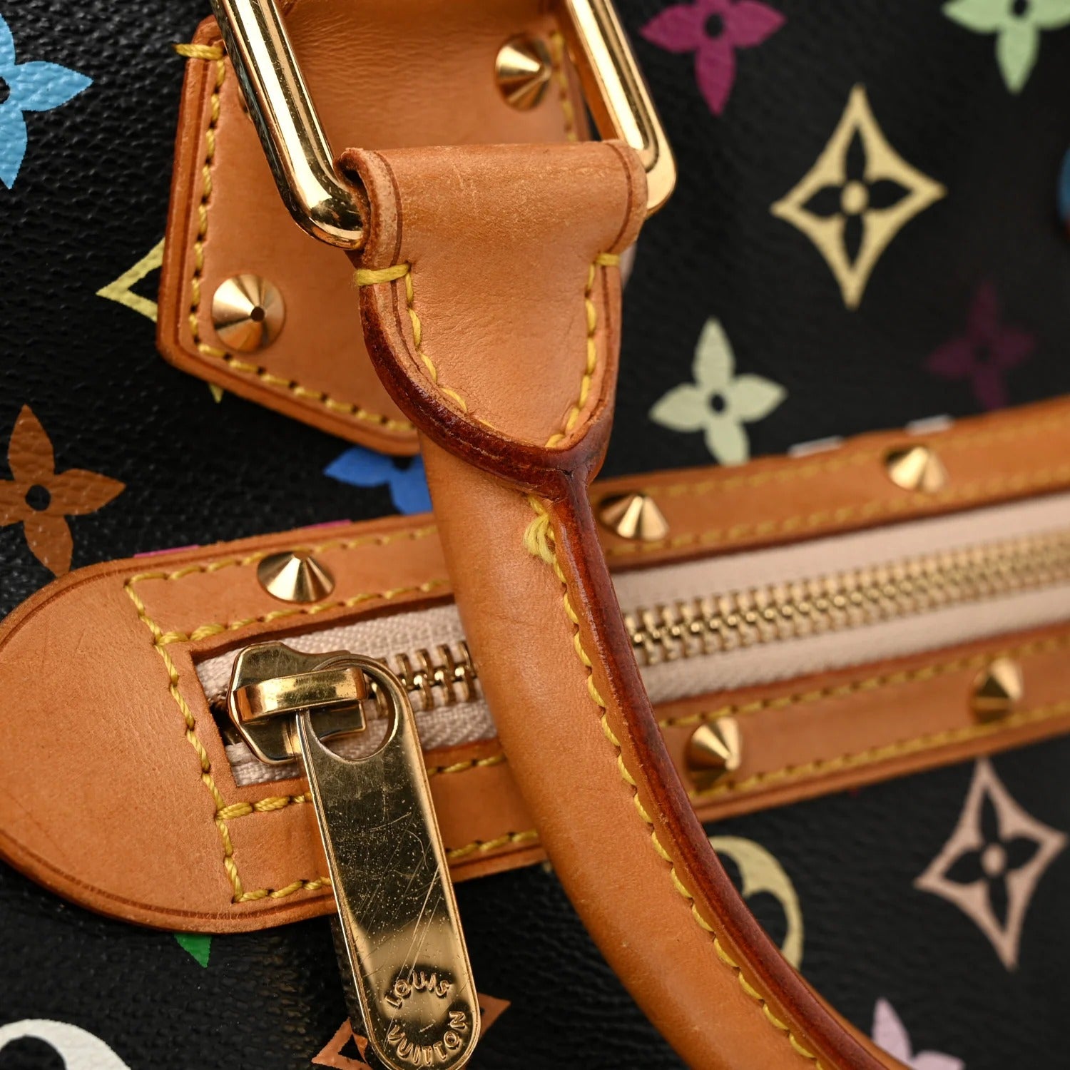 Close-up of a brown leather handbag with gold hardware on a multicolor patterned background.
