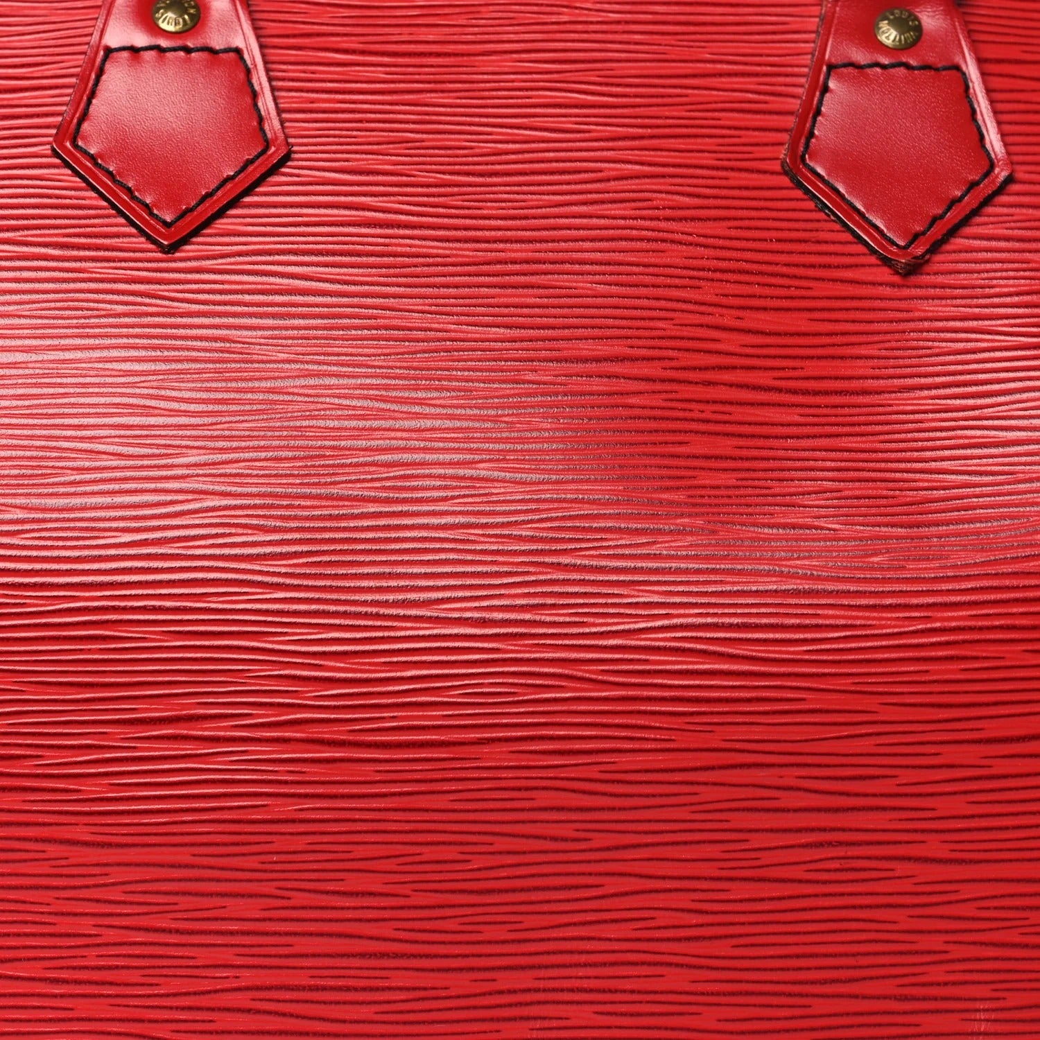Close-up of a red textured leather surface with gold accents.