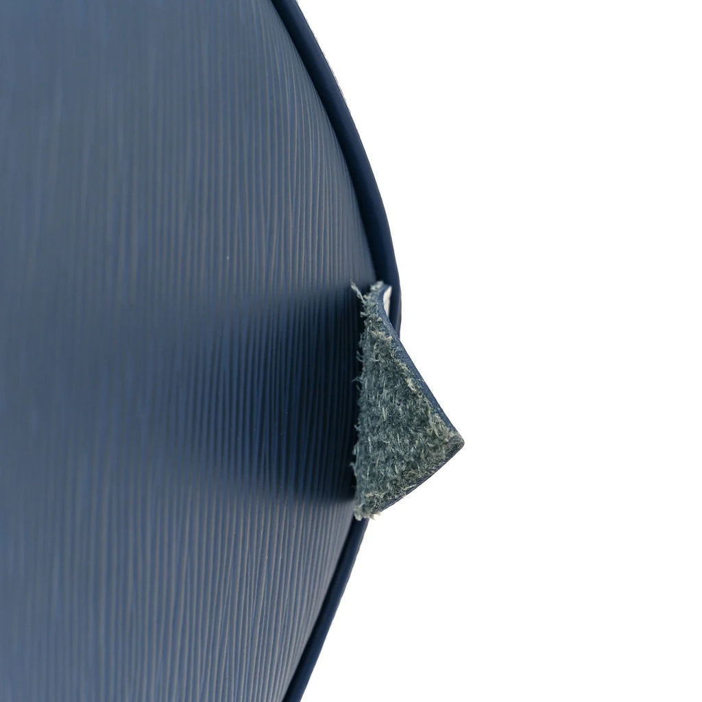 louis vuitton epi speedy Close-up of a textured blue surface with a corner cut out, revealing a white interior.