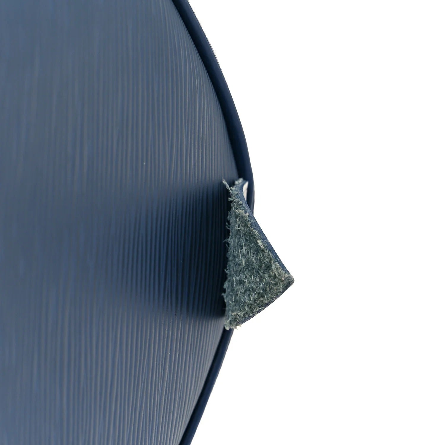 louis vuitton epi speedy Close-up of a textured blue surface with a corner cut out, revealing a white interior.