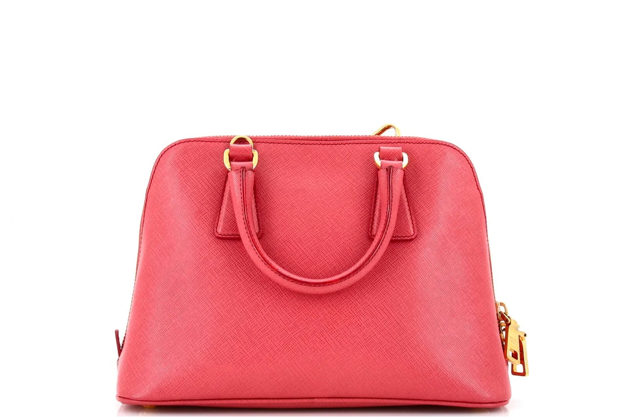 Pink Prada leather handbag with gold accents on a white background