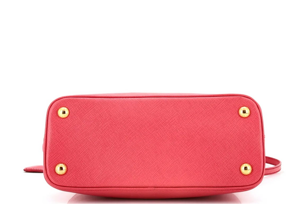 Pink Prada leather handbag with gold accents on a white background