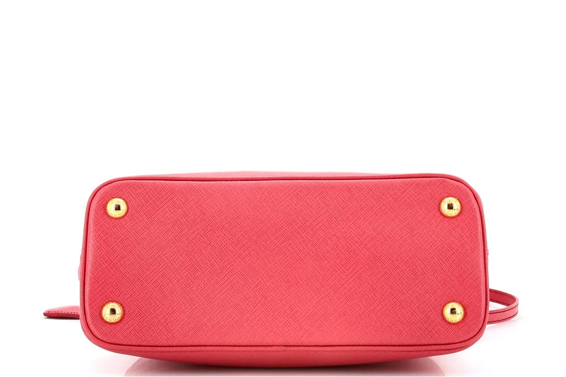 Pink Prada leather handbag with gold accents on a white background