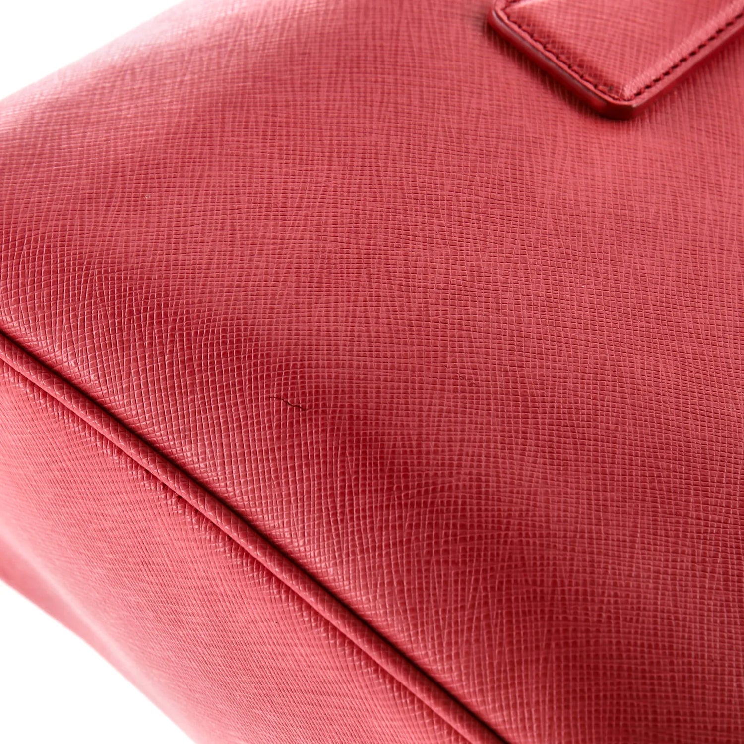 Close-up of a Pink Prada leather textured handbag with a white background