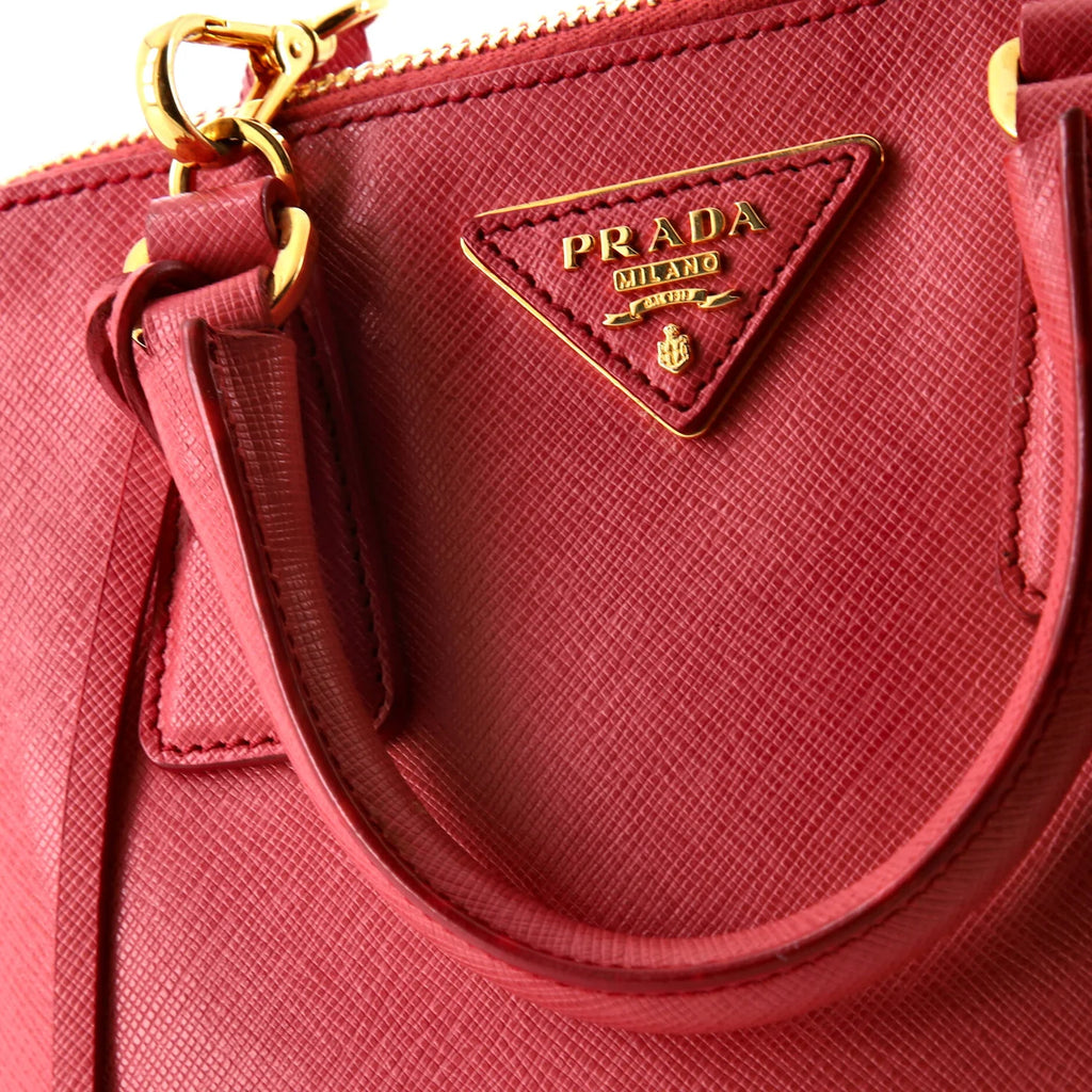 Close-up of a pink Prada handbag with gold accents.