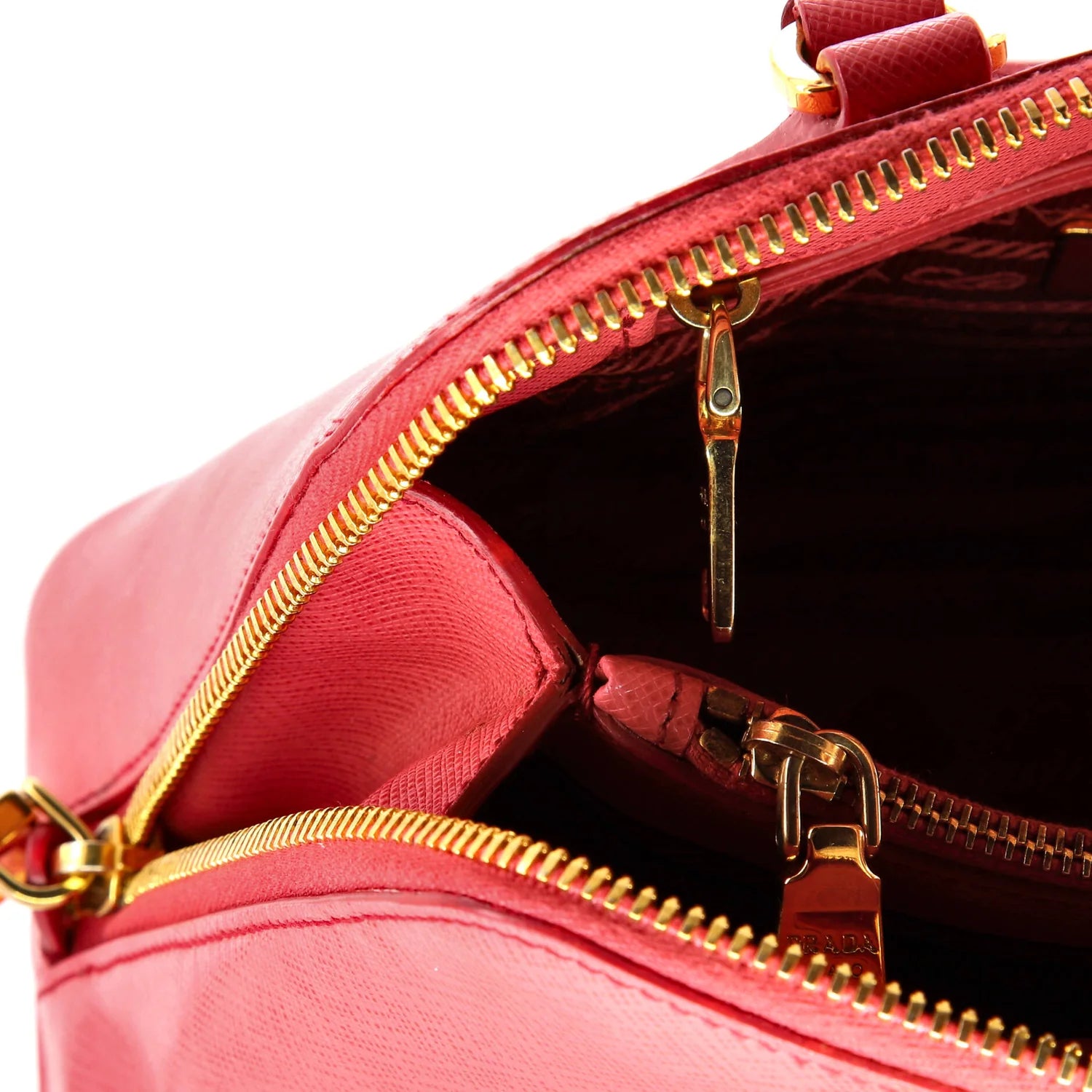 Close-up of a Pink Prada leather handbag with gold zippers on a white background