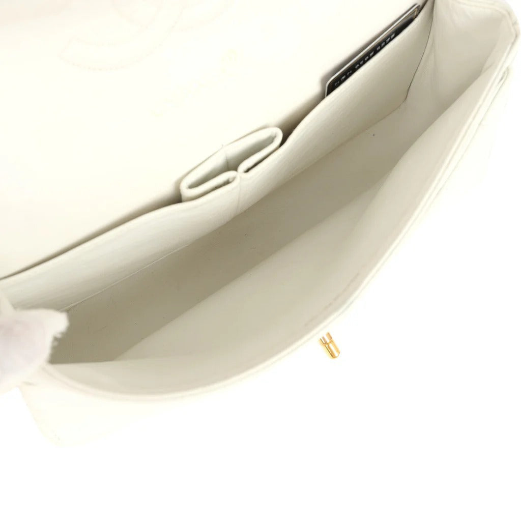 Close-up of a beige handbag with a gold clasp on a white background vintage chanel caviar white medium double flap 