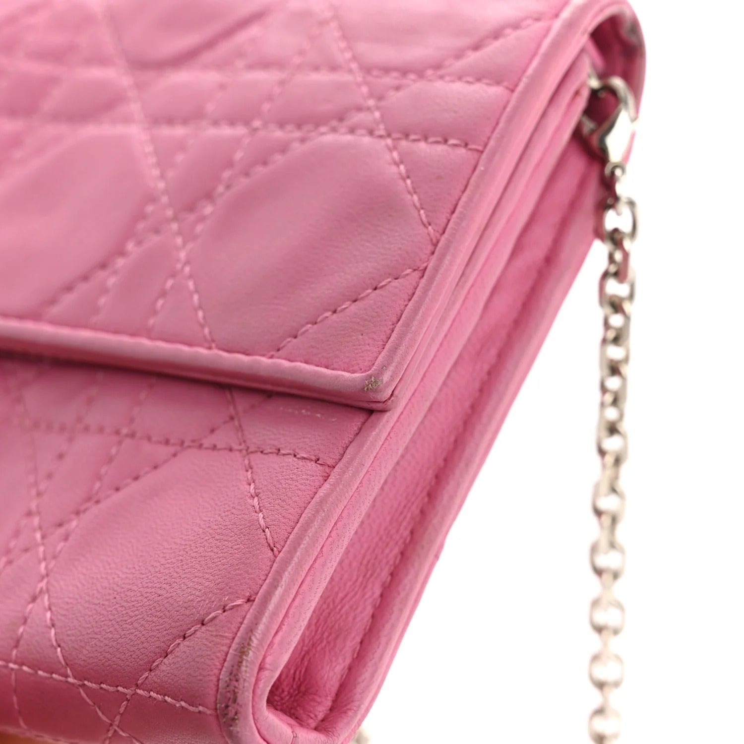 Close-up of a pink quilted handbag with a chain strap on a white background